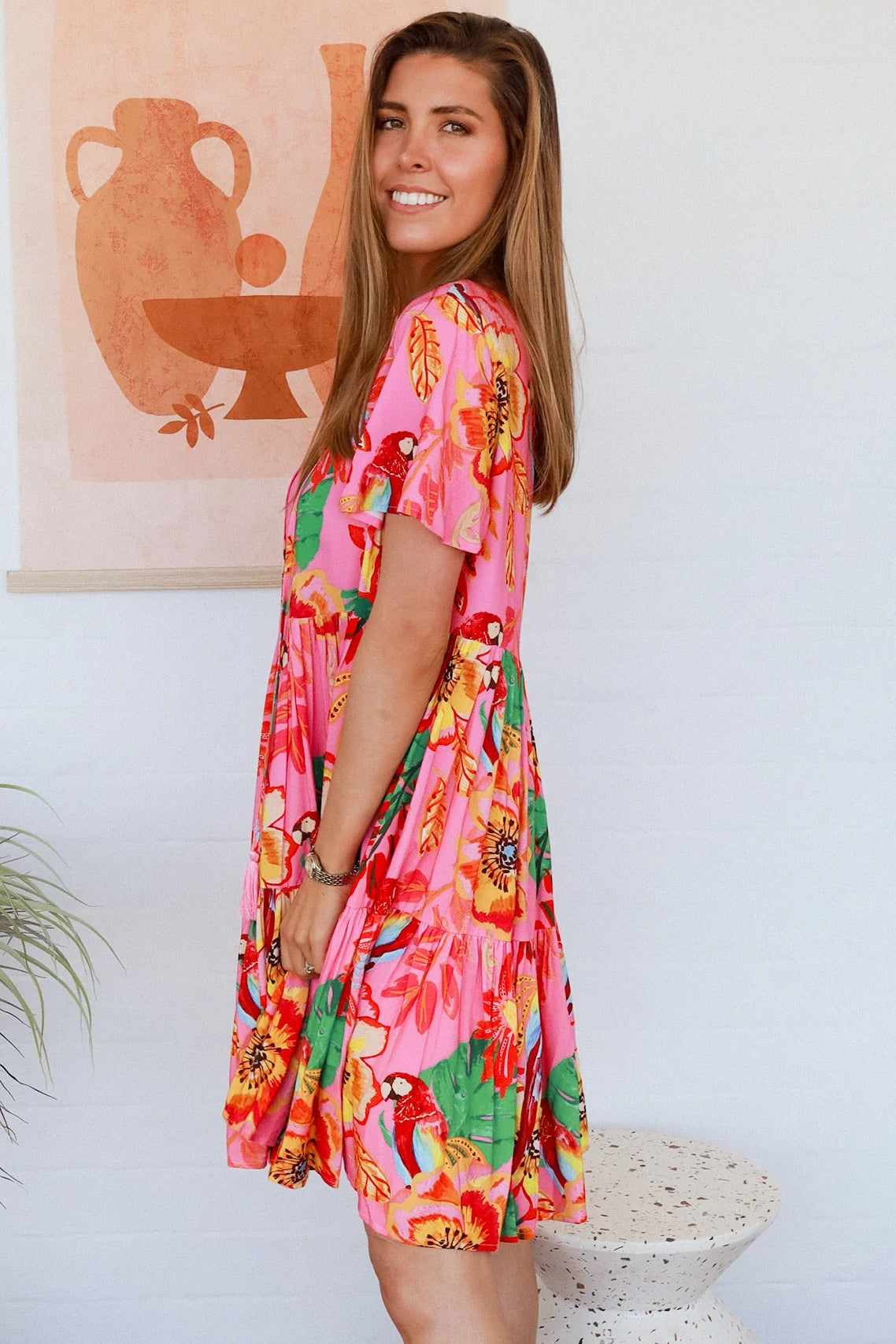 Pink floral mini dress with poppy and parrot print, V-neck button bodice, tassel ties and flutter sleeves