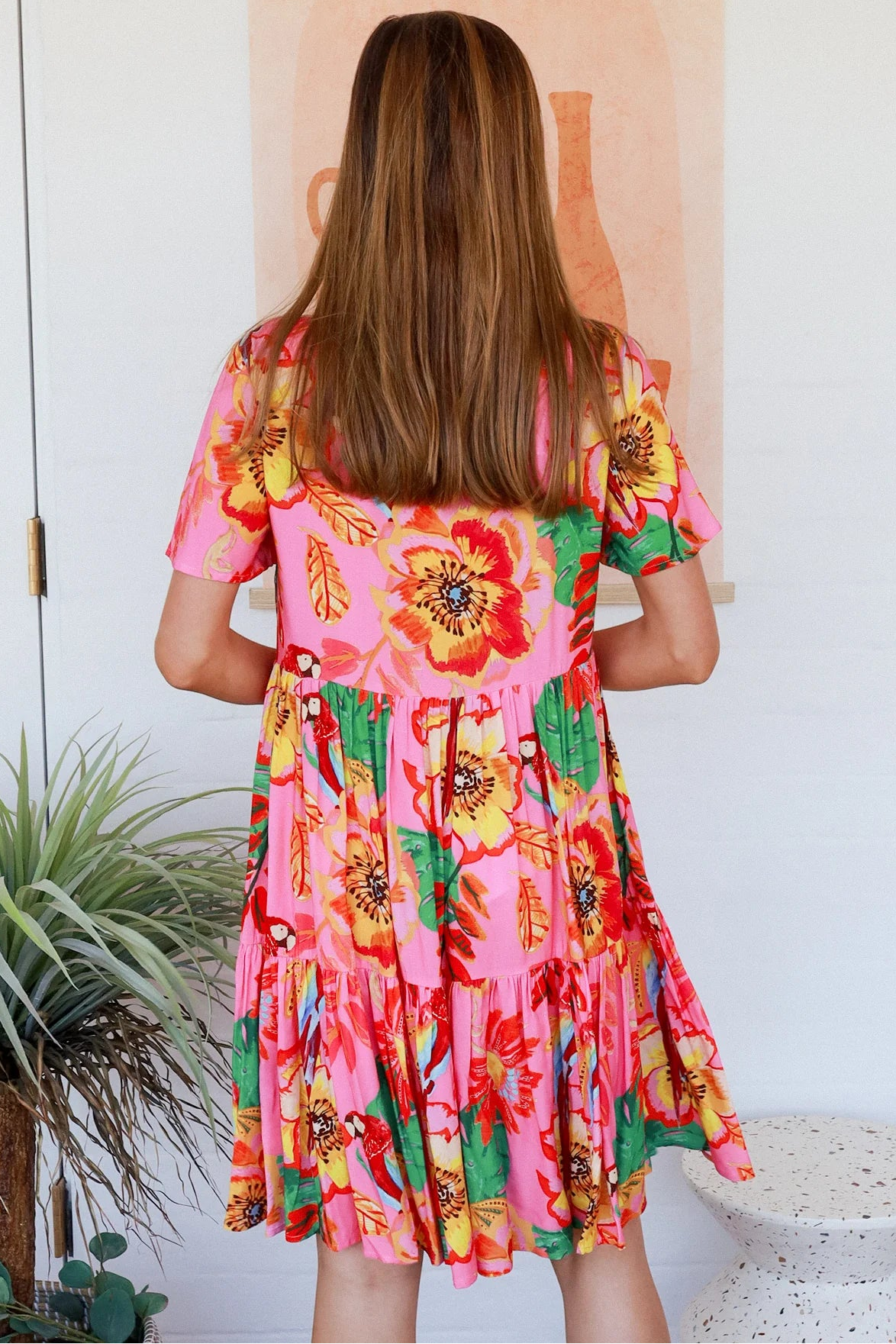 Pink floral mini dress with poppy and parrot print, V-neck button bodice, tassel ties and flutter sleeves