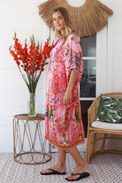 “Woman in pink floral viscose crepe kaftan midi dress with rhinestone buttons by Peacock Feathers – bohemian resort wear Australia”