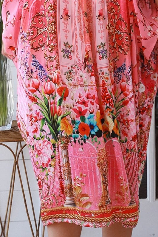 “Woman in pink floral viscose crepe kaftan midi dress with rhinestone buttons by Peacock Feathers – bohemian resort wear Australia”