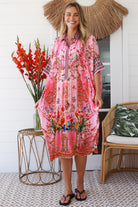“Woman in pink floral viscose crepe kaftan midi dress with rhinestone buttons by Peacock Feathers – bohemian resort wear Australia”
