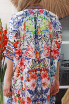 Woman in white viscose crepe kaftan midi dress with coral, jade and cobalt florals by Peacock Feathers Resort Luxe – Boho Dresses Australia