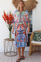 Woman in white viscose crepe kaftan midi dress with coral, jade and cobalt florals by Peacock Feathers Resort Luxe – Boho Dresses Australia