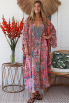 Woman in rose floral linen-viscose kimono with turquoise accents and side splits - Peacock Feather Resort Luxe