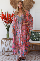 Woman in rose floral linen-viscose kimono with turquoise accents and side splits - Peacock Feather Resort Luxe