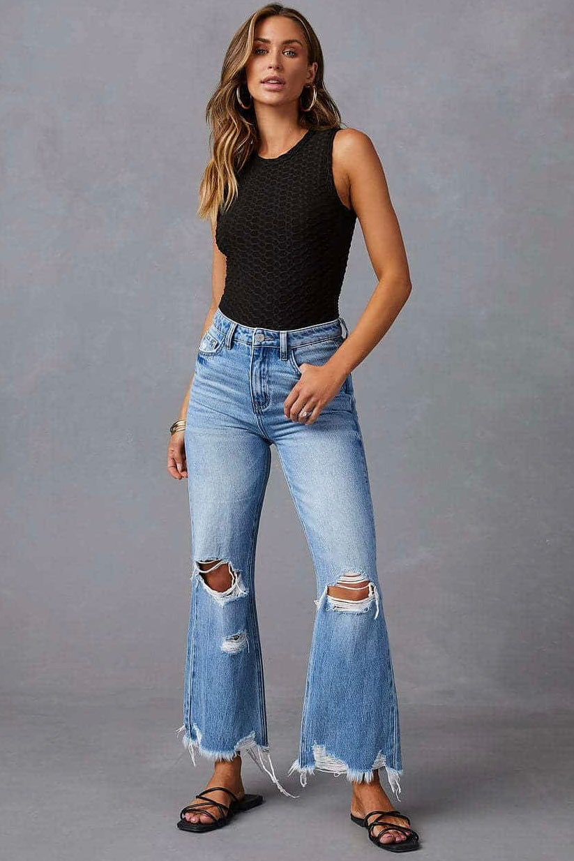 Woman wearing high-waisted light blue wide-leg jeans with raw hem and black tank - boho denim jeans Australia.