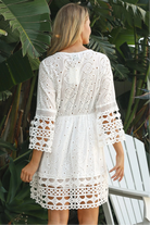 Woman in white cotton embroidered mini dress with daisy crochet waist and fluted bell sleeves – boho summer style