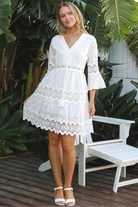 Woman in white embroidered anglaise cotton mini dress with crochet trims and scalloped tiers – Australian boho fashion