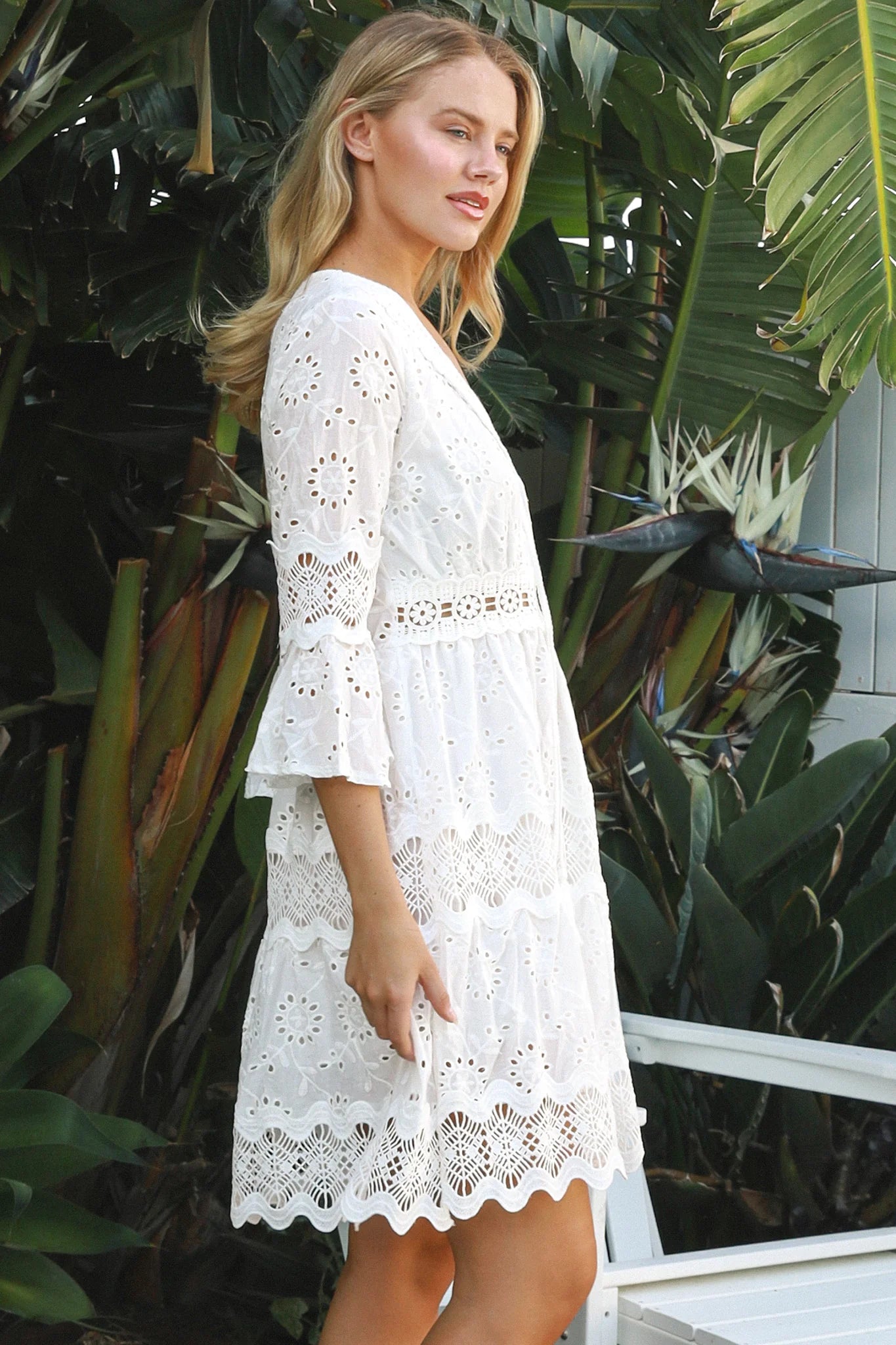 Woman in white embroidered anglaise cotton mini dress with crochet trims and scalloped tiers – Australian boho fashion