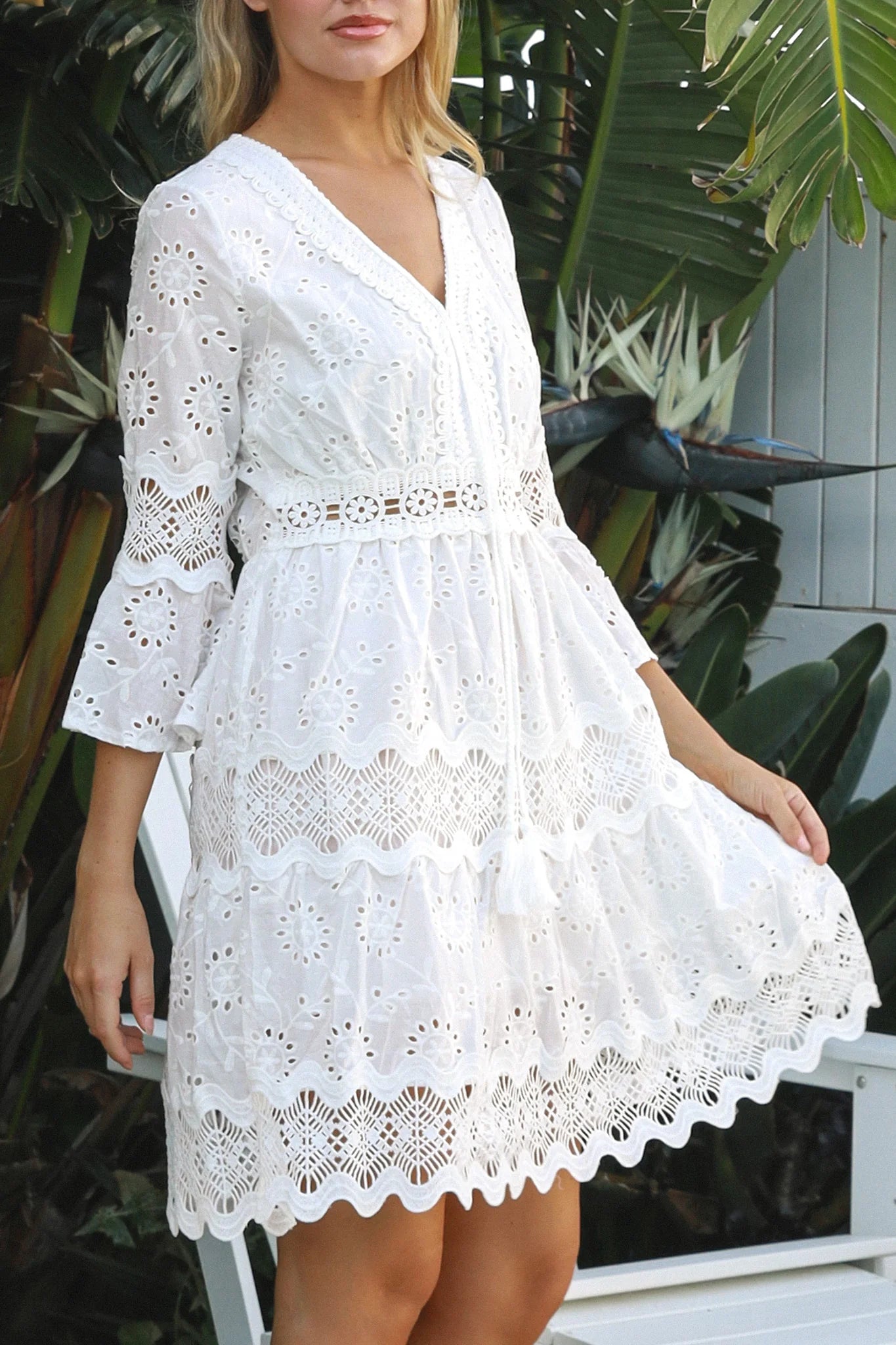 Woman in white embroidered anglaise cotton mini dress with crochet trims and scalloped tiers – Australian boho fashion