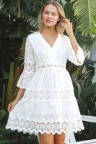 Woman in white embroidered anglaise cotton mini dress with crochet trims and scalloped tiers – Australian boho fashion