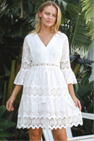 Woman in white embroidered anglaise cotton mini dress with crochet trims and scalloped tiers – Australian boho fashion