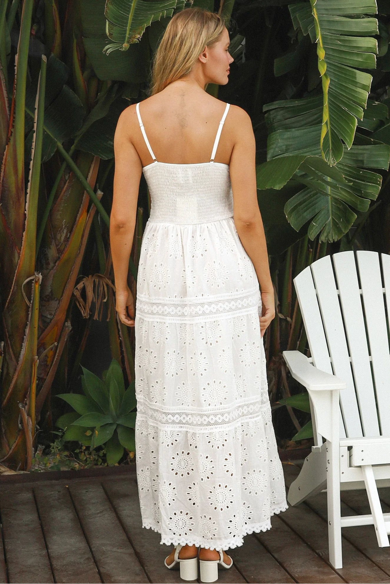 White embroidered cotton maxi dress with lace-trim neckline and scalloped tiered skirt in natural summer light.