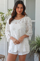 White embroidered cotton top with scalloped hem and three quarter sleeves styled for summer