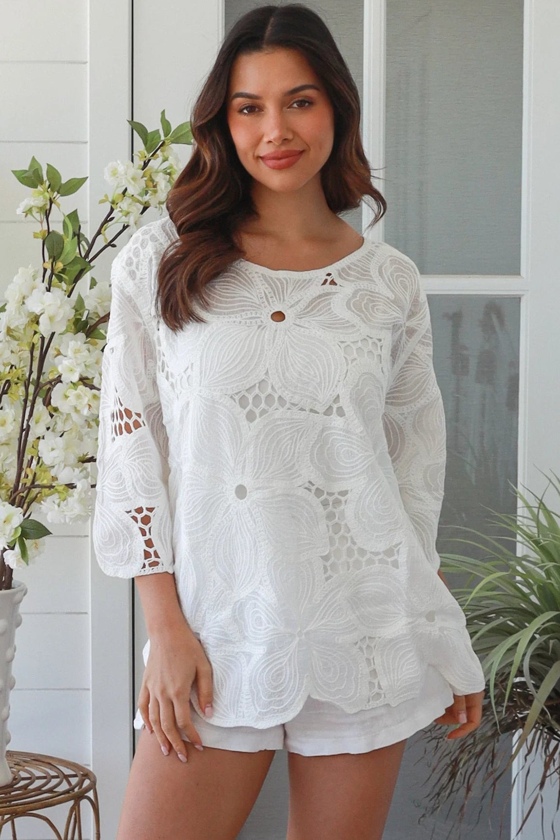 White embroidered cotton top with scalloped hem and three quarter sleeves styled for summer