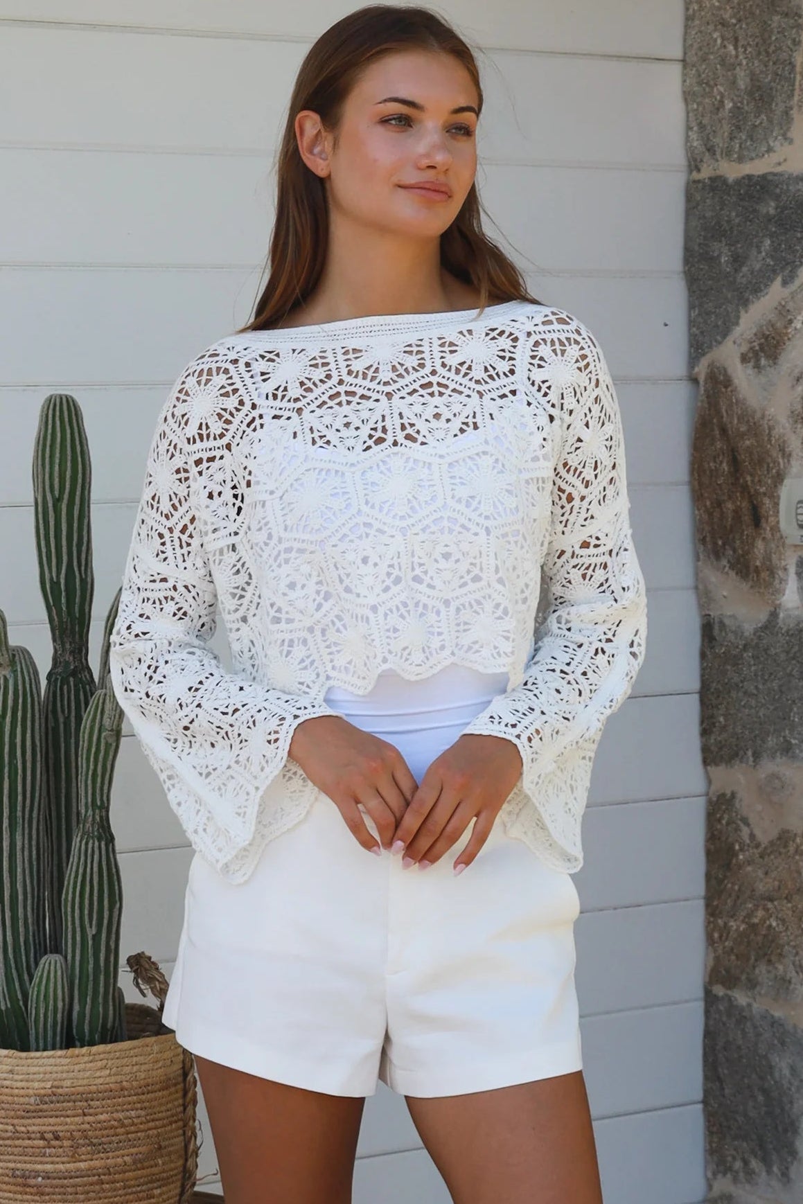 Woman wearing white crochet cotton boho top with long sleeves styled with white shorts Australian fashion