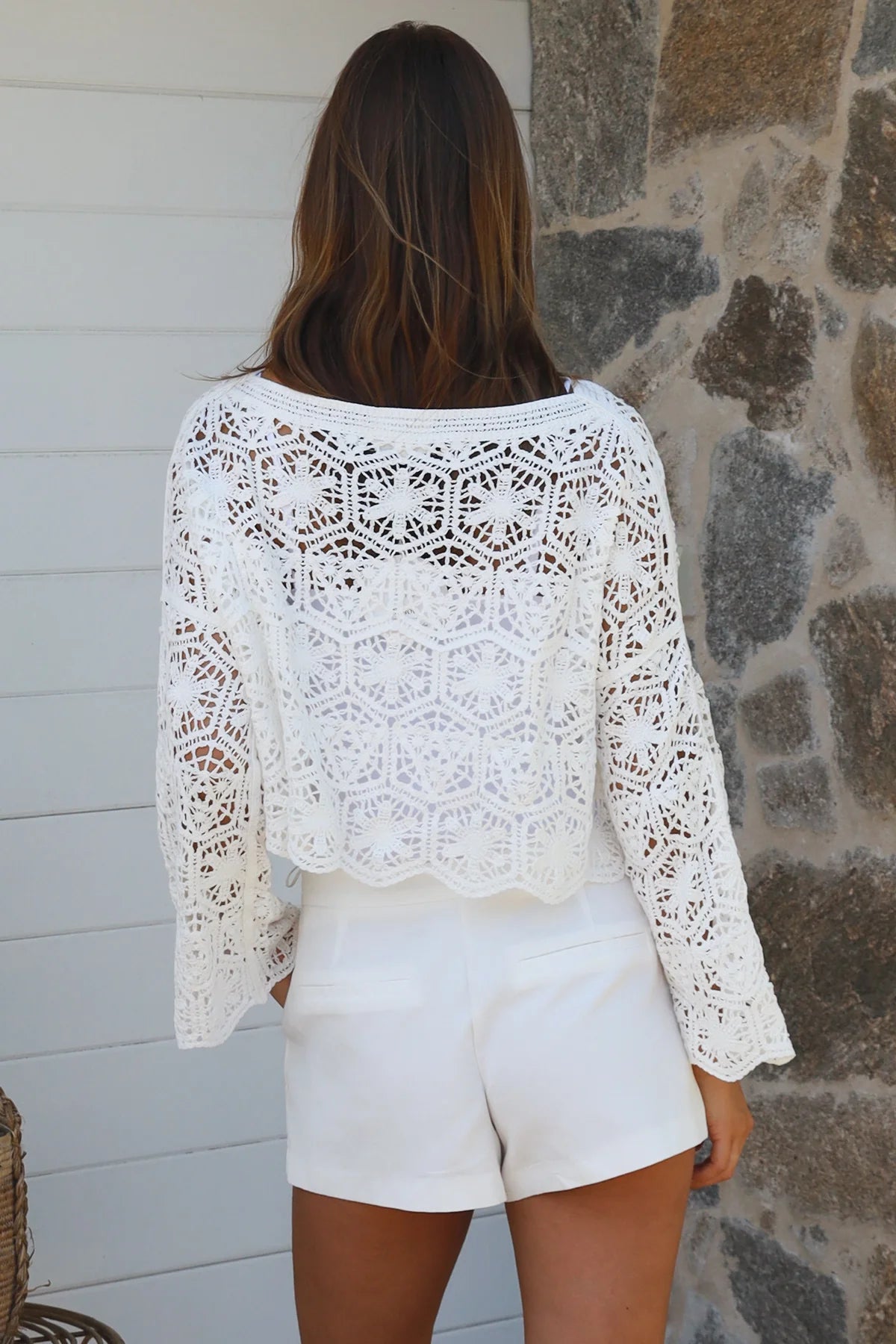 Woman wearing white crochet cotton boho top with long sleeves styled with white shorts Australian fashion