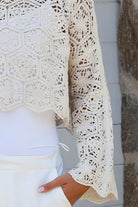 Cream crochet cotton long sleeve crop top with scalloped hem and flared cuffs styled with white shorts