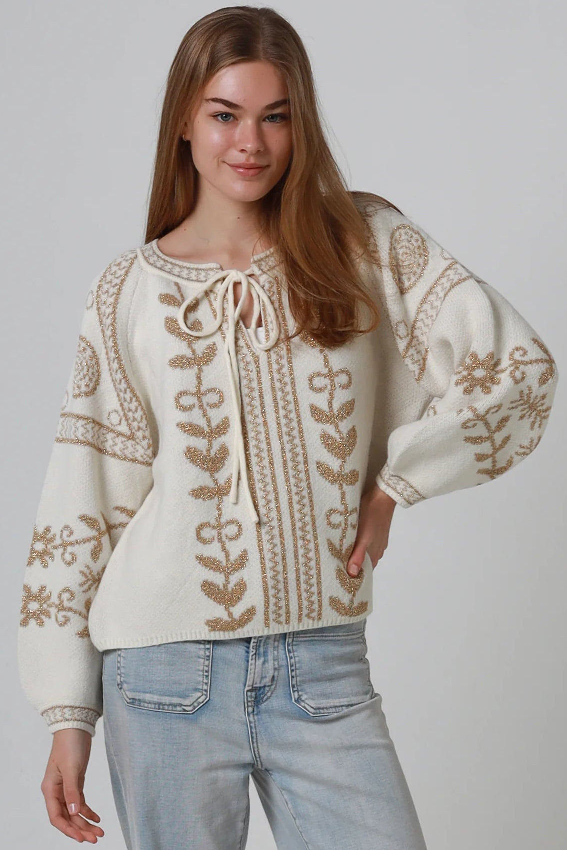 Woman wearing cream boho knit jumper with golden lurex detailing, balloon sleeves and relaxed winter styling.