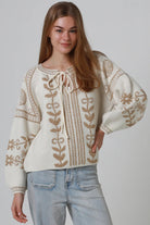 Woman wearing cream boho knit jumper with golden lurex detailing, balloon sleeves and relaxed winter styling.
