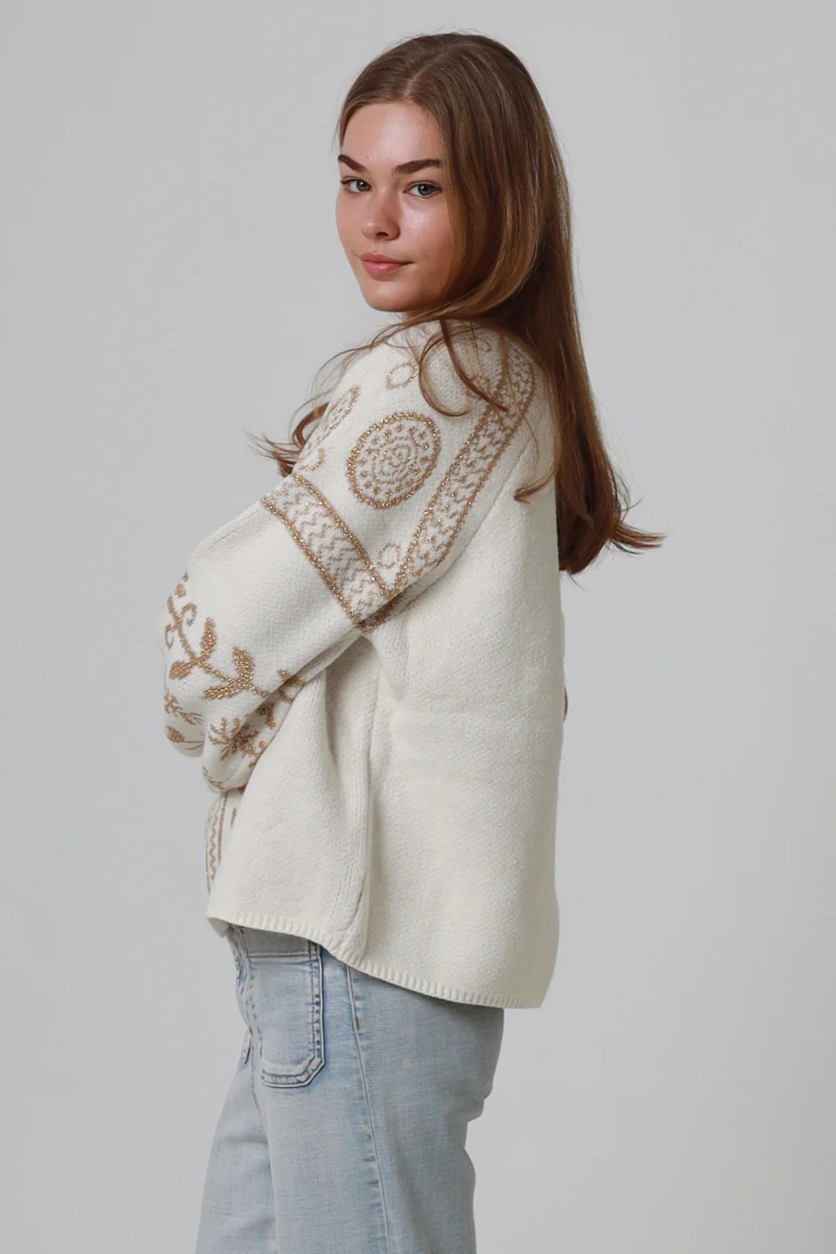 Woman wearing cream boho knit jumper with golden lurex detailing, balloon sleeves and relaxed winter styling.