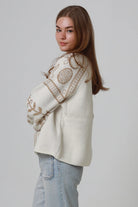 Woman wearing cream boho knit jumper with golden lurex detailing, balloon sleeves and relaxed winter styling.