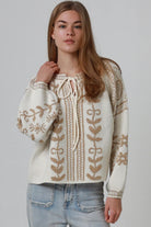 Woman wearing cream boho knit jumper with golden lurex detailing, balloon sleeves and relaxed winter styling.
