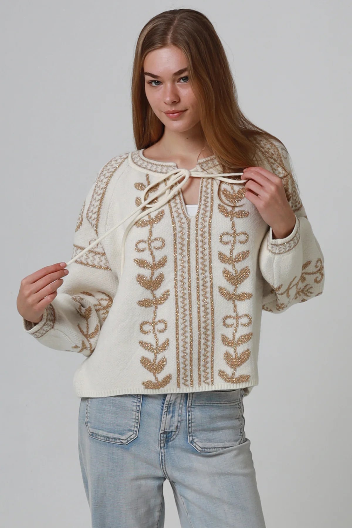 Woman wearing cream boho knit jumper with golden lurex detailing, balloon sleeves and relaxed winter styling.