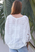Woman wearing oversized white embroidered cotton crochet blouse with airy sleeves and relaxed coastal bohemian styling in Australia