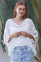 Woman wearing oversized white embroidered cotton crochet blouse with airy sleeves and relaxed coastal bohemian styling in Australia