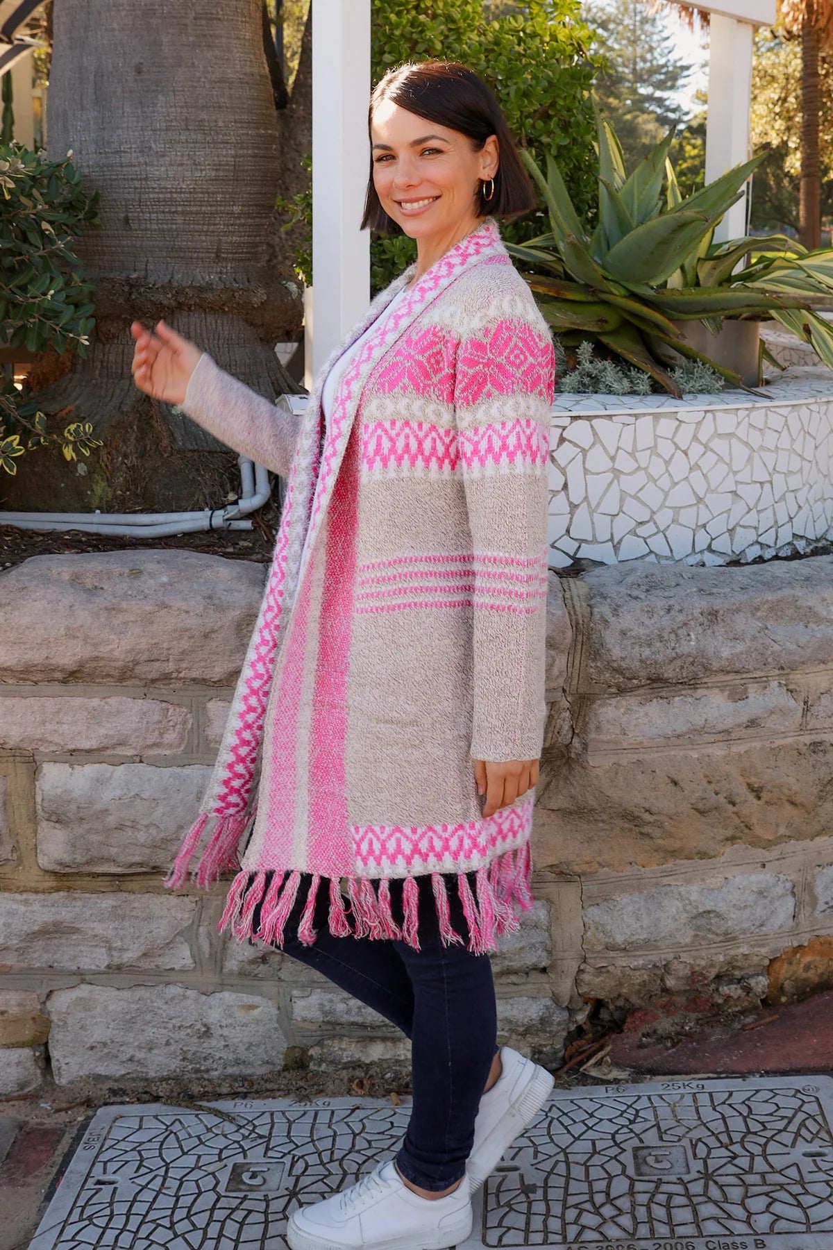 Woman wearing longline rose pink and cream boho knit cardigan with fringe hem - Australian winter fashion.