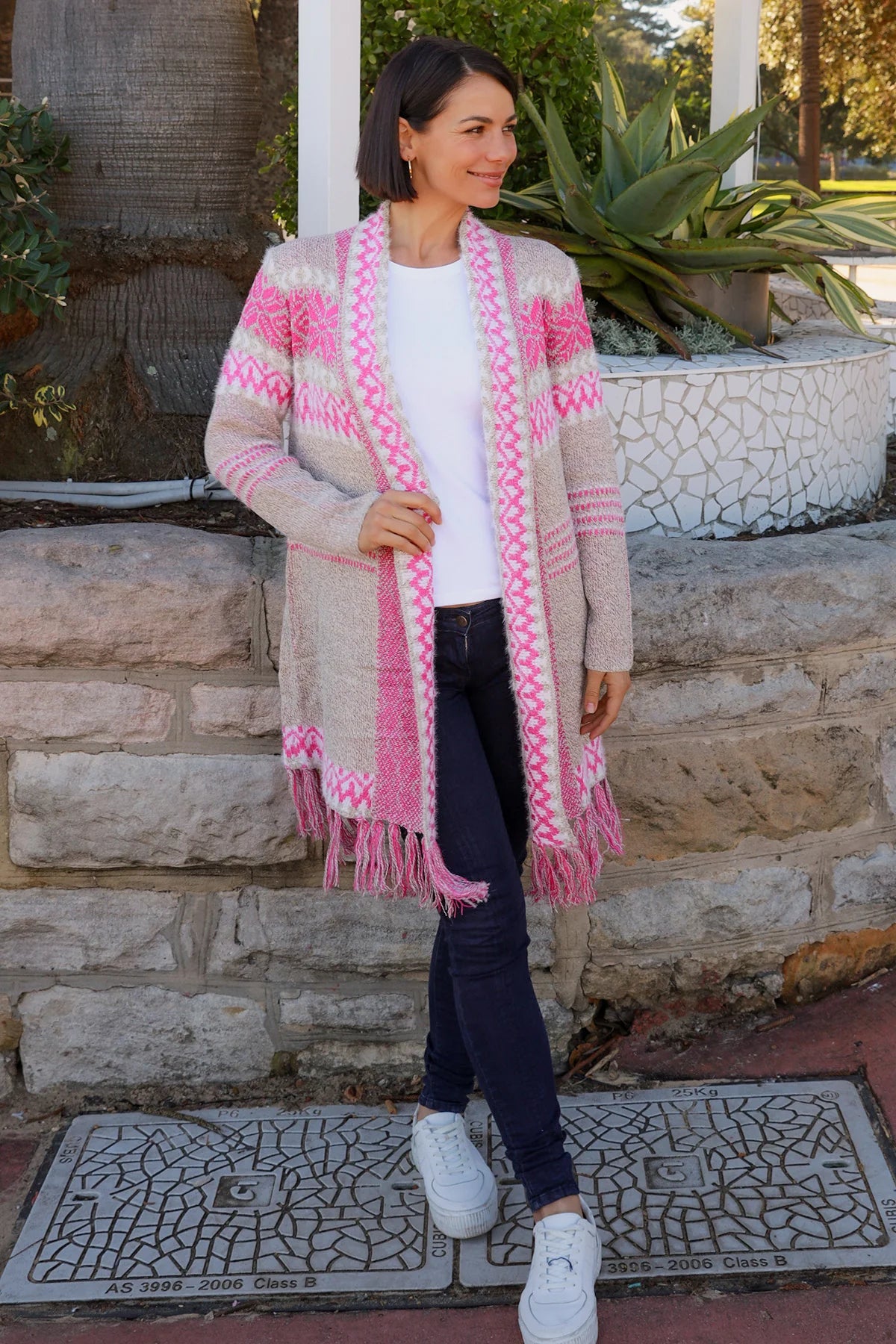 Woman wearing longline rose pink and cream boho knit cardigan with fringe hem - Australian winter fashion.