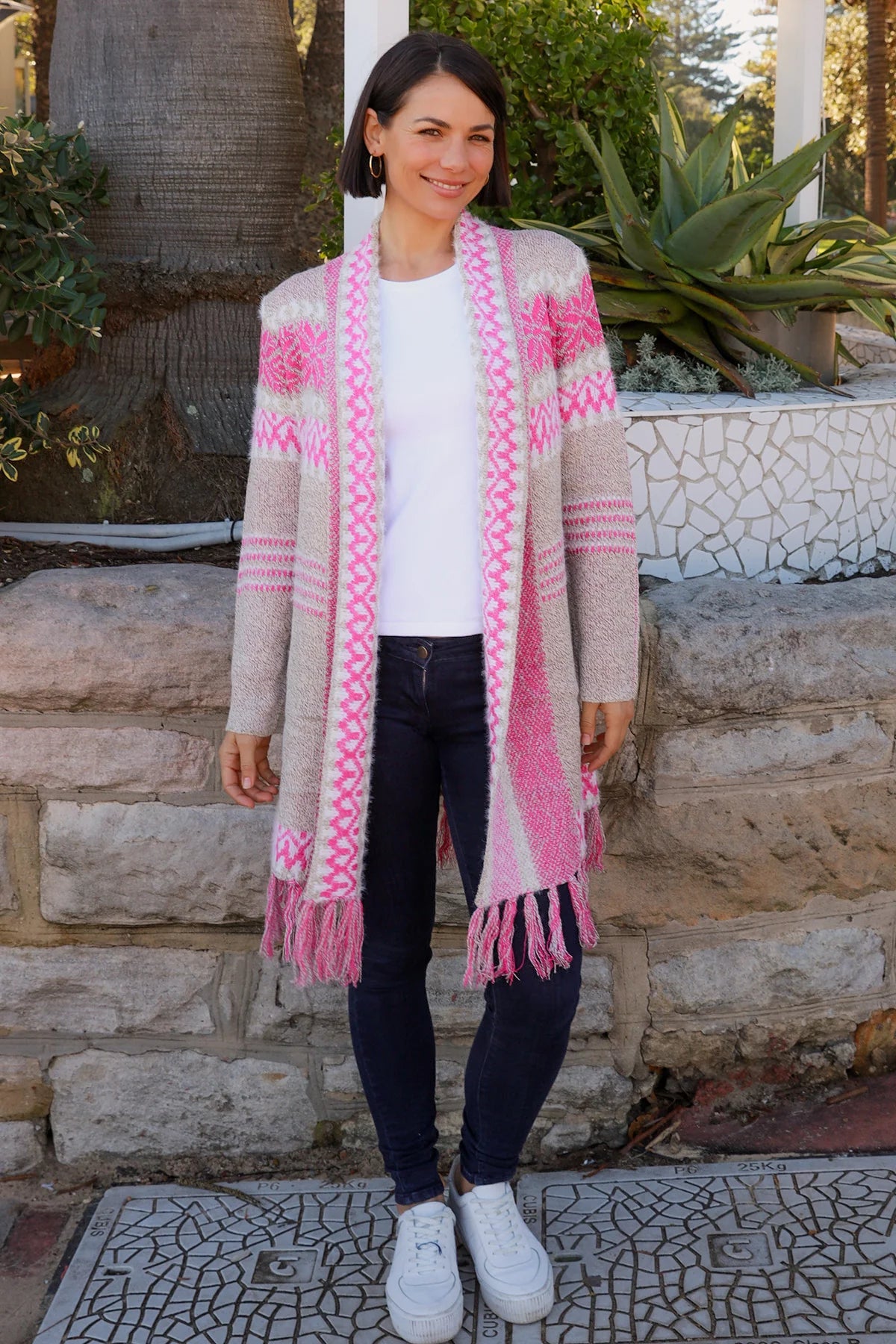 Woman wearing longline rose pink and cream boho knit cardigan with fringe hem - Australian winter fashion.
