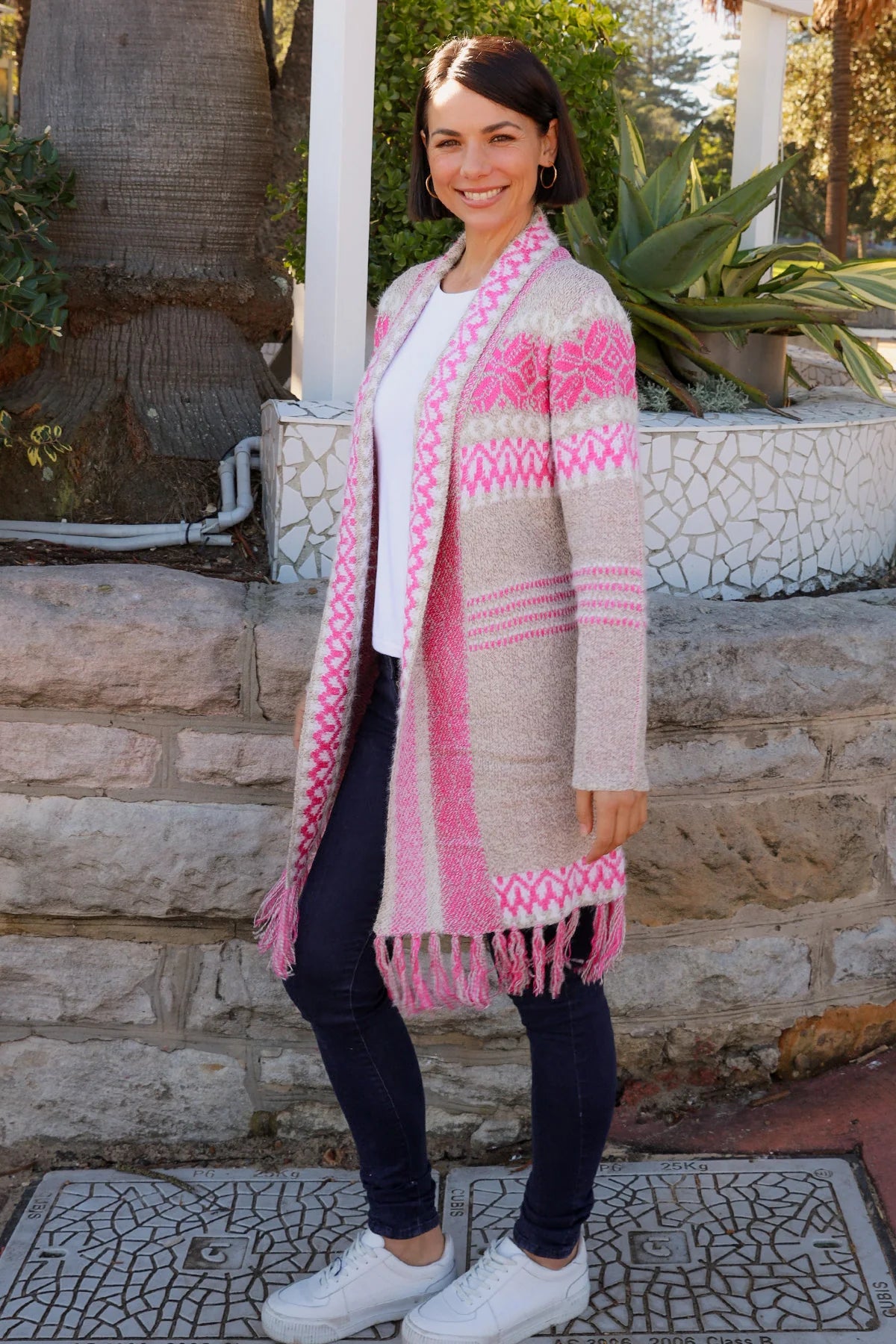 Woman wearing longline rose pink and cream boho knit cardigan with fringe hem - Australian winter fashion.