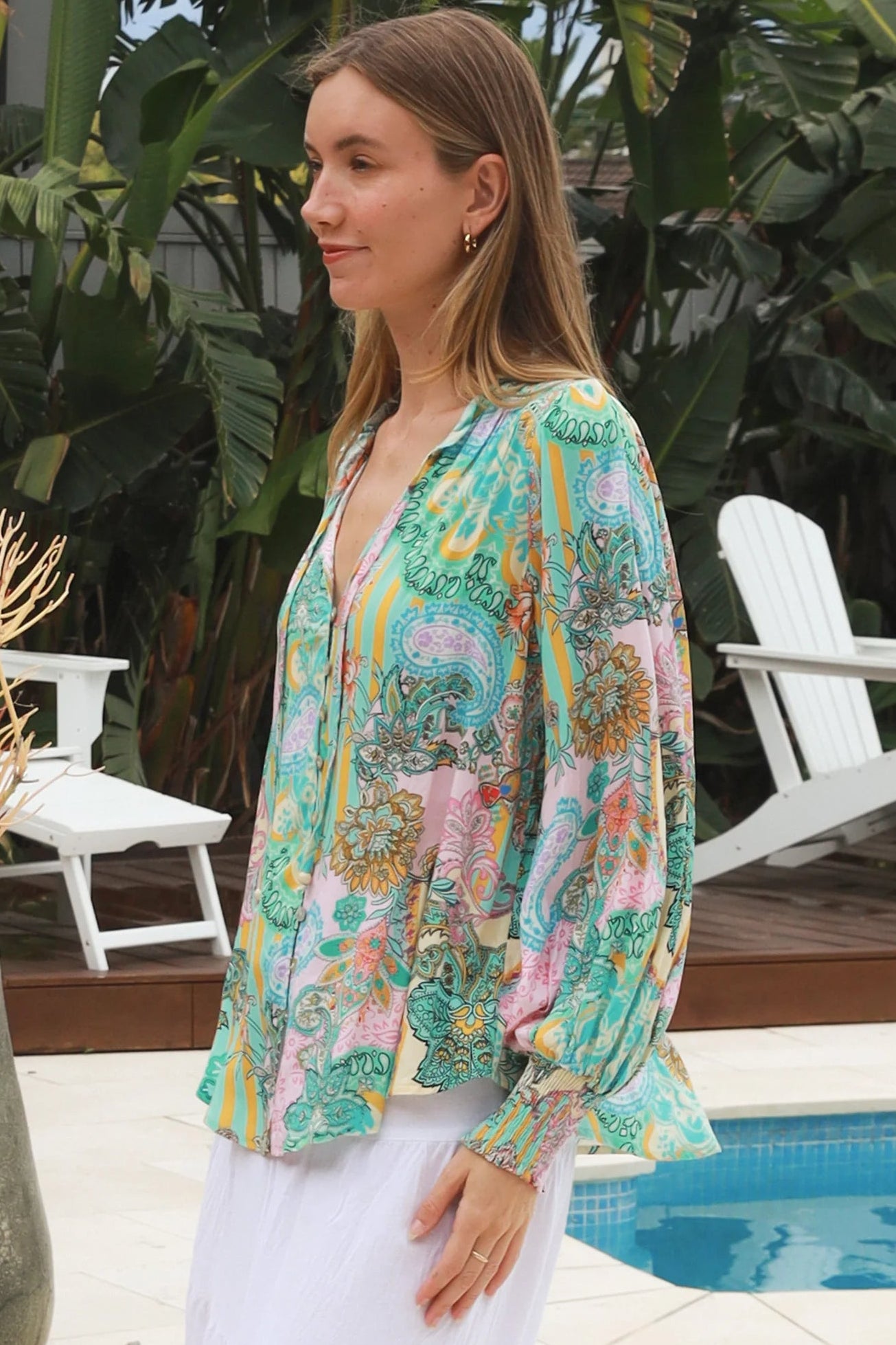 Woman wearing Salty Palm Mika Blouse in green patchwork rayon with V-neck tie, cotton lace shoulders and crochet yoke