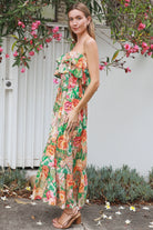 Model wearing a Dreamcatcher Raya strapless floral patchwork maxi dress in green and pink with ruffle bodice and tiered skirt