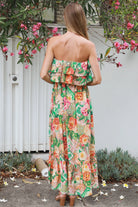 Model wearing a Dreamcatcher Raya strapless floral patchwork maxi dress in green and pink with ruffle bodice and tiered skirt