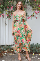 Model wearing a Dreamcatcher Raya strapless floral patchwork maxi dress in green and pink with ruffle bodice and tiered skirt