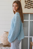 Woman wearing pastel blue crochet knit sweater styled with denim for a refined boho winter outfit Australia