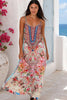 Model walking wearing the Peacock Feather Mirage floral maxi dress with adjustable straps and rhinestone embellished bodice