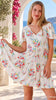 Model in motion wearing the Salty Palm ivory floral boho mini dress in rayon with V-neck, flutter sleeves, drawstring waist and oversized frill hem at Bohemian Love Runway 