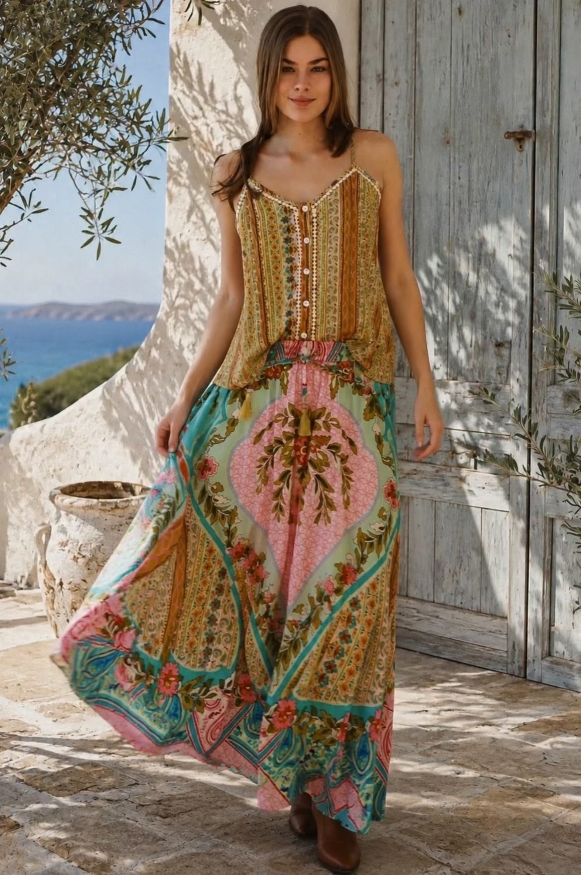 Model in motion wearing the Amara floral boho maxi skirt in 100% rayon with colourful placement print, gathered frill hem and tassel tie from Bohemian Love Runway.