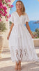 Model in motion wearing the Aurelia white embroidered cotton maxi dress with lace panels, v-neckline, tassel ties and tiered skirt at Bohemian Love Runway.