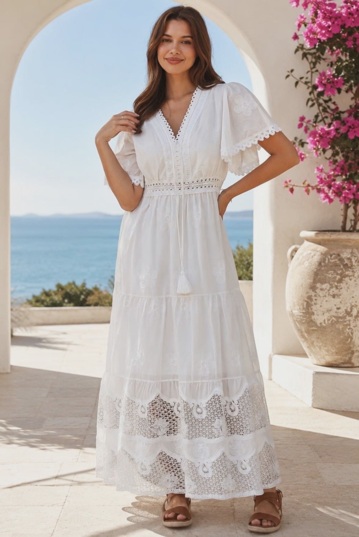 Model in motion wearing the Willow white embroidered cotton maxi dress with openwork lace and tassel ties by Salty Palm at Bohemian Love Runway