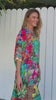 Woman wearing a tropical print viscose linen midi dress with bright coral, aqua, and green hues walking through sunlight - Resort Luxe bohemian style Australia