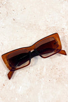 Woman in brown oversized cat eye sunglasses with sleek bun and black top - vintage boho style Australia.