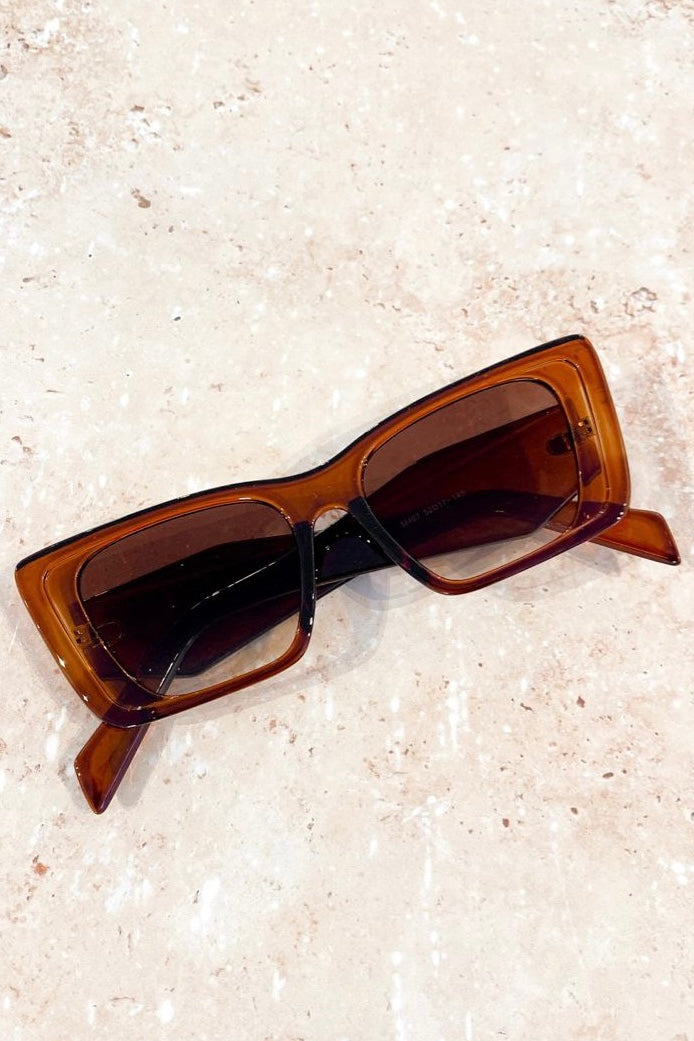 Woman in brown oversized cat eye sunglasses with sleek bun and black top - vintage boho style Australia.
