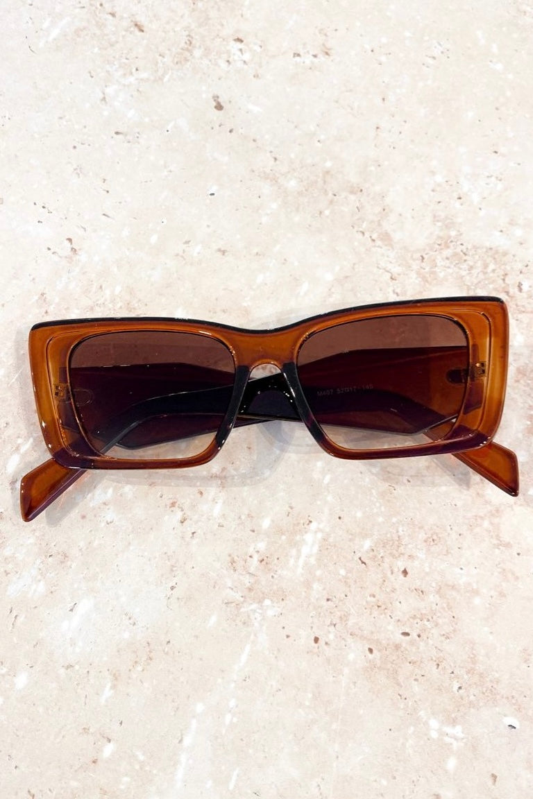 Woman in brown oversized cat eye sunglasses with sleek bun and black top - vintage boho style Australia.
